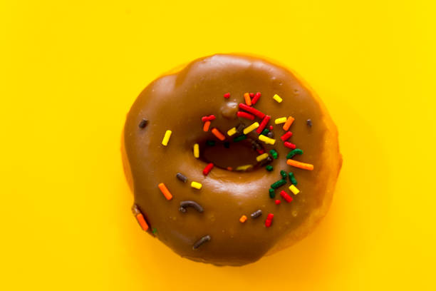 istock Glazed Chocolate Doughnut with Sprinkles,Yellow Background 1422341181