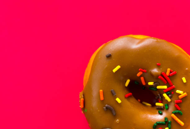 istock Glazed Chocolate Doughnut with Sprinkles, Red Background 1422341195