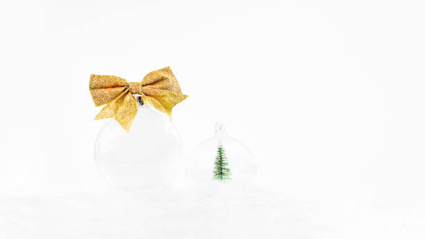 new year's card background.close-up.poster.transparent glass ball with a gold bow lies on the snow on a light bokeh background. - decor christmas celebration event christmas ornament imagens e fotografias de stock