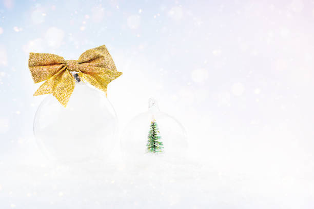 pôster do baner para a composição do ano novo. composição natalina de uma bola transparente com um arco dourado em um fundo leve com neve e bokeh. bola de natal para a árvore. - celebration holidays and celebrations bow christmas - fotografias e filmes do acervo