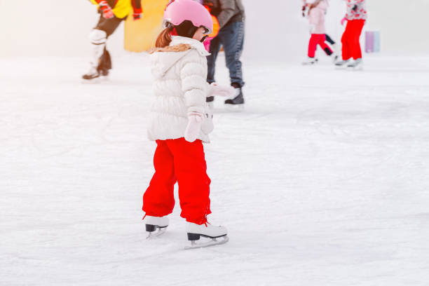 adorable petit kisd en vêtements d’hiver avec des protections patinant sur la patinoire. un enfant de 3-5 ans, apprendre le train, monter sur la patinoire de la ville d’hiver, patiner sur glace. outdoor.sports d’hiver. - 12 13 years 13 14 years learning education photos et images de collection