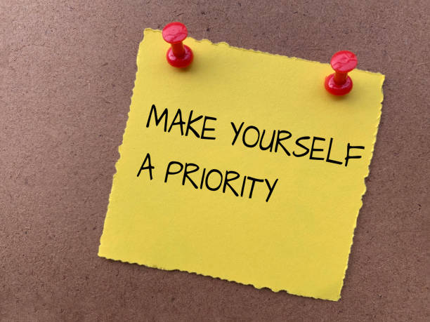istock Make yourself a priority text on yellow notepad with wooden background. Motivational concept 1422363324