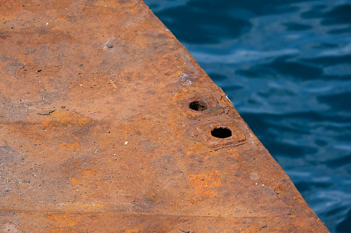 Close-up of a rusty ferry ramp against the water of tropical sea. transportation and travel concept