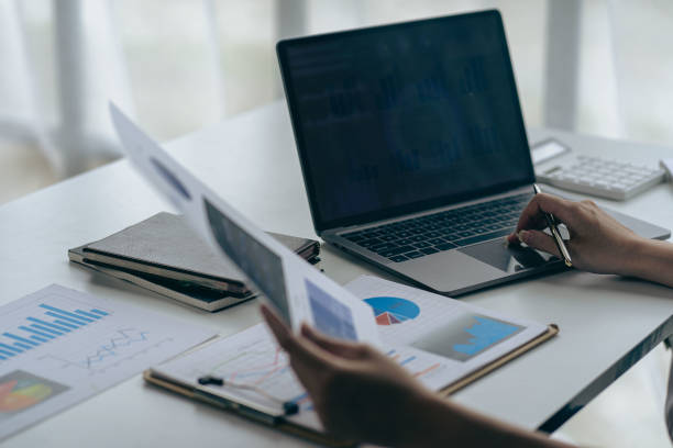 istock businessman holding pen and pie chart document showing company financial data He sits in a private office with a laptop analyzing financial data in chart form. financial concept 1422384934