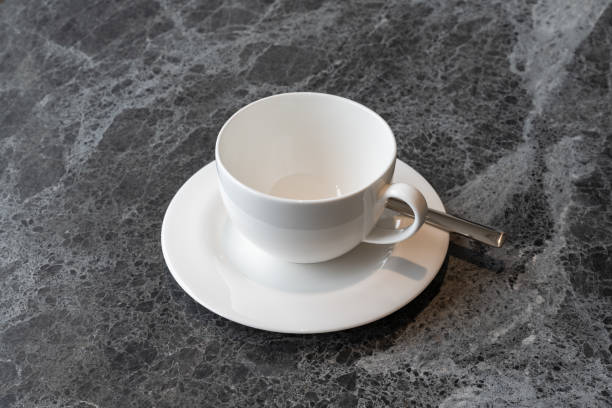 white cup with teaspoon on stone table stock photo