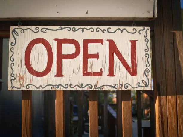 Hand painted sign advising OPEN in red lettering on board with rustic look.