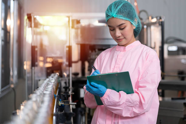 manufacturer checking product bottles fruit juice on the conveyor belt in the beverage factory. woman worker checks product bottles in beverage factory. inspection quality control - food safety imagens e fotografias de stock