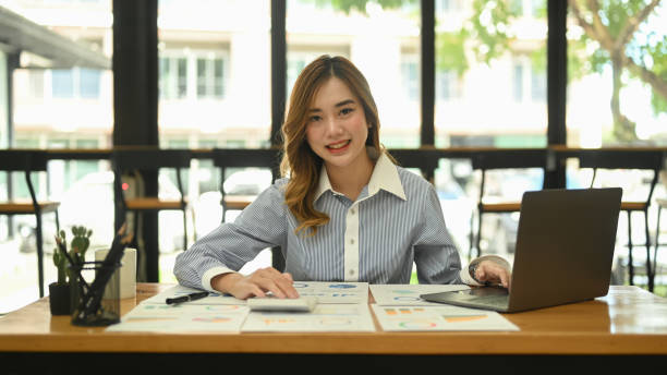 istock Beautiful female employee using laptop computer at bright modern corporate office. 1422405776