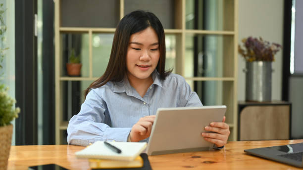 istock Beautiful female employee using laptop computer at bright modern corporate office. 1422405816