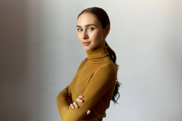 istock Side view of confident determened independent young female with folded arms looking at camera on white background with copy space for your promotional content wearing business casual turtleneck 1422416372