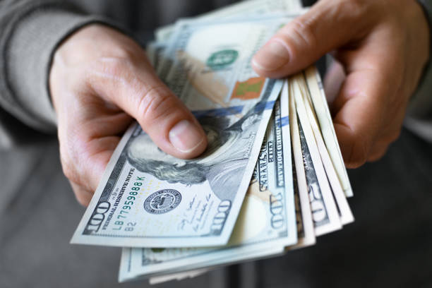 istock White female model shows dollar bills in her hand closeup front view 1422421593