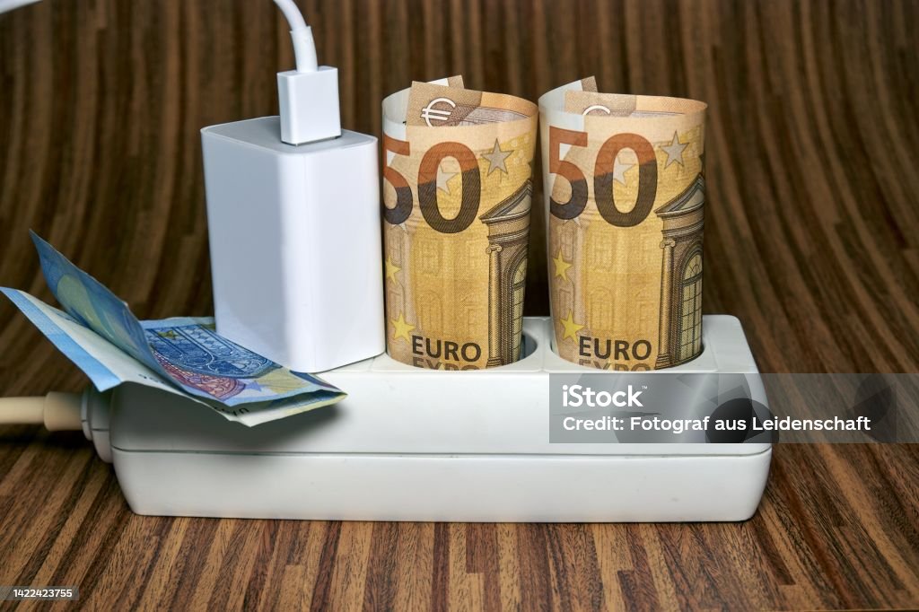 Electric socket with 50 euro bill . Rising electricity prices and costly energy concept for families and businesses Electric socket with 50 euro bill . Rising electricity prices and costly energy concept for families and businesses. Aiming Stock Photo