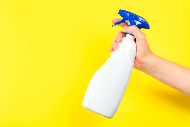 istock Hand holding a plastic spray bottle against yellow background 1422426136