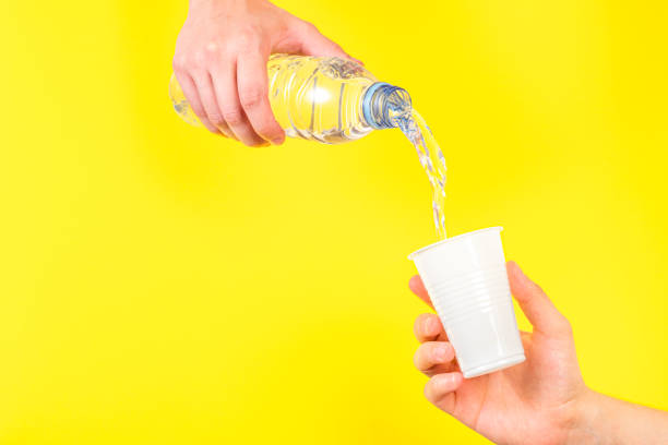 istock Pouring water into a disposable cup on yellow background 1422426163