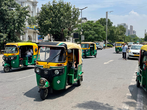 Connaught Place, New Delhi, India - August 21, 2022: Auto rickshaws parked up and transporting passengers from Connaught Place, one of the largest business, commercial and financial centres in New Delhi, India.