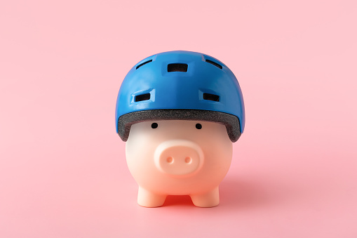 Piggy bank in blue helmet on pink background. Financial protection and insurance concept