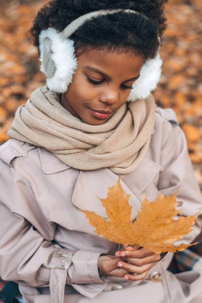 portret uroczej afroamerykańskiej dziewczyny z liściem klonu w rękach w jesiennym parku. różnorodność, jesienna koncepcja - maple leaf audio zdjęcia i obrazy z banku zdjęć