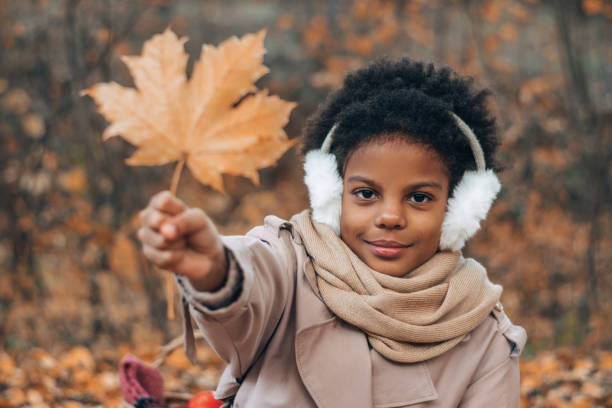 Portrait of a cute African-American girl with a maple leaf in her hands in an autumn park.Diversity,autumn concept