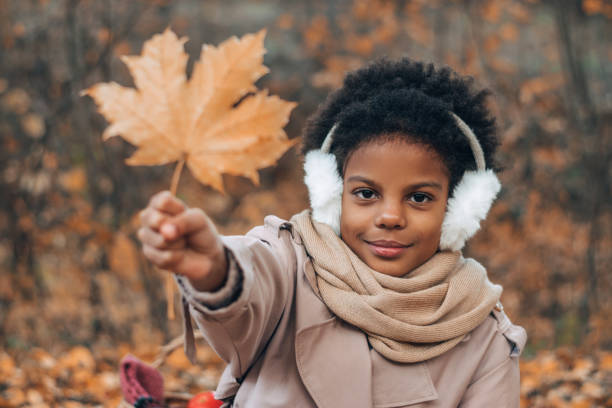 portret uroczej afroamerykańskiej dziewczyny z liściem klonu w rękach w jesiennym parku. różnorodność, jesienna koncepcja - maple leaf audio zdjęcia i obrazy z banku zdjęć