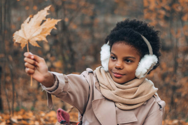 portret uroczej afroamerykańskiej dziewczyny z liściem klonu w rękach w jesiennym parku. różnorodność, jesienna koncepcja - maple leaf audio zdjęcia i obrazy z banku zdjęć