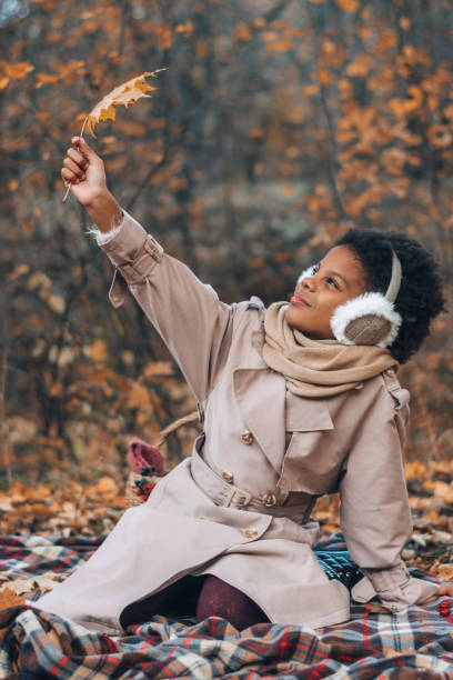 portret uroczej afroamerykańskiej dziewczyny z liściem klonu w rękach w jesiennym parku. różnorodność, jesienna koncepcja - maple leaf audio zdjęcia i obrazy z banku zdjęć