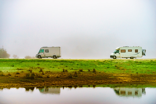 Camping on nature. Two camper vehicles at lake shore, foggy weather. Povoa e Meadas Dam in Castelo de Vide, Alentejo Portugal. Travel in wintertime.