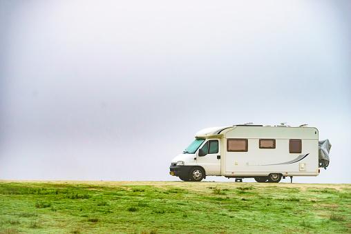 Camping on nature. Camper vehicle at campsite on foggy day. Travel in wintertime.