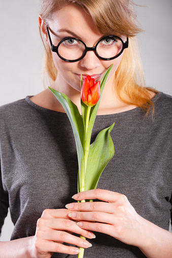 Peace and content. Beauty adorable girl smelling beautiful spring flower. Peaceful enjoyable woman with red green tulip. Lady smell nature.