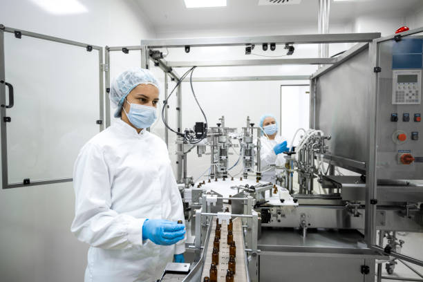 istock Two female employees in a pharmaceutical laboratory seen while controlling the process of drugs manufacturing stock 1422442953