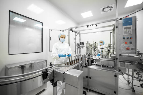 istock Two female employees in a pharmaceutical laboratory seen while controlling the process of drugs manufacturing stock 1422443009