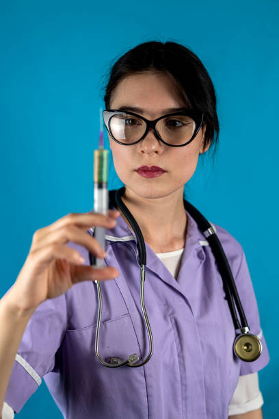 Photo of cheerful positive female doctor wearing white coat holding syringe smiling isolated solid color background. portrait of a woman with a syringe. the concept of injections. injection treatment