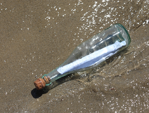 transparent glass bottles with cork stoppers with a secret message found on the seashore carried by the waves