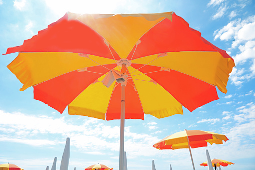 under a large yellow and orange umbrella on the sunny beach symbol of summer