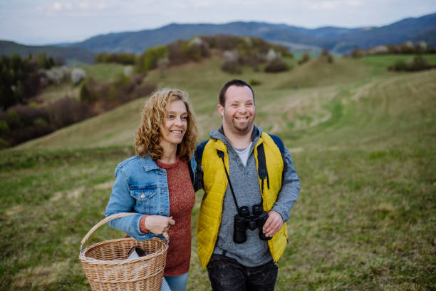 Portrait of happy young man with Down syndrome with his mother hiking together in nature. A portrait of happy young man with Down syndrome with his mother hiking together in nature. disabled person hiking outdoors stock pictures, royalty-free photos & images