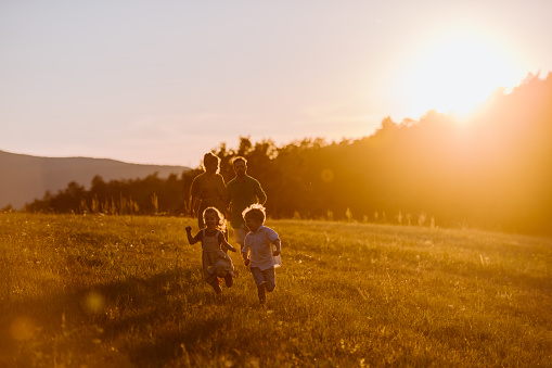 A happy young family spending time together outside in nature during sunset.