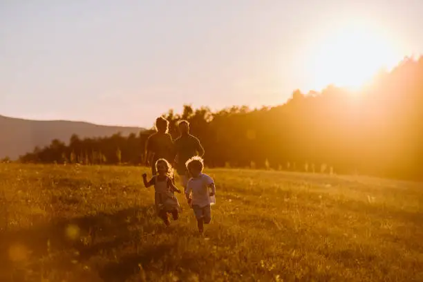 A happy young family spending time together outside in nature during sunset.