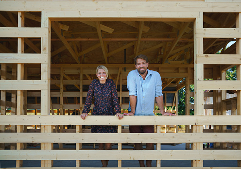 A young couple on site inside construction framing dreaming of her new home.