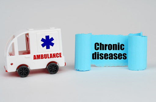 Medical concept. On a white surface, an ambulance and a blue paper sign with the inscription - Chronic diseases