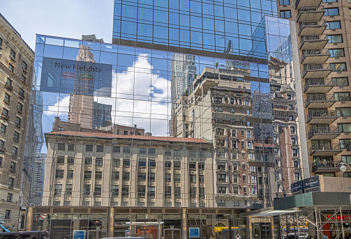 Manhattan, New York, NY, USA - July 13th 2022:  Old brick building mirrored in a façade of a modern steel and glass building on Broadway close to West 54th Street