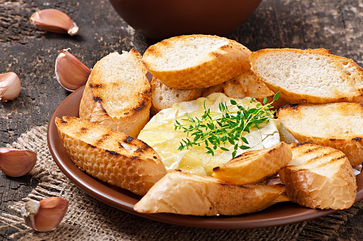 Baked Camembert cheese with thyme and toast rubbed with garlic