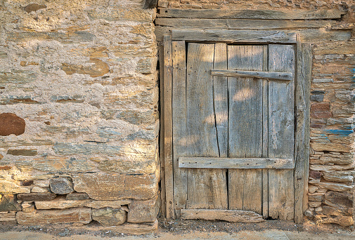 Rustic wooden door on adobe building wall with copy space