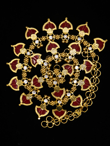 women's antique golden necklace jewelry with red and white luxurious stones isolated in a black background