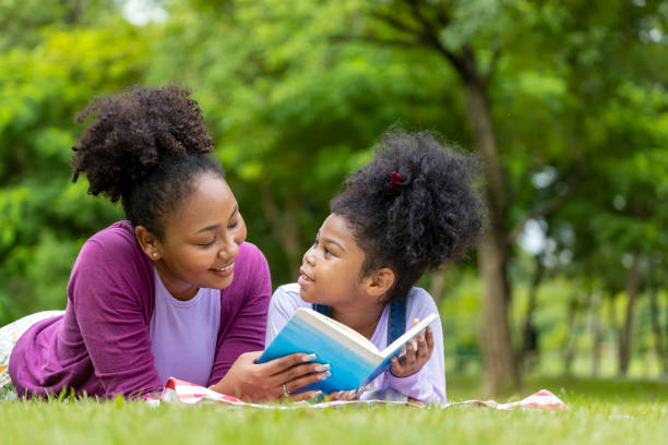 istock African American mother is teaching her young daughter to read while lying down after having a summer picnic in the public park for education and happiness concept 1422477733