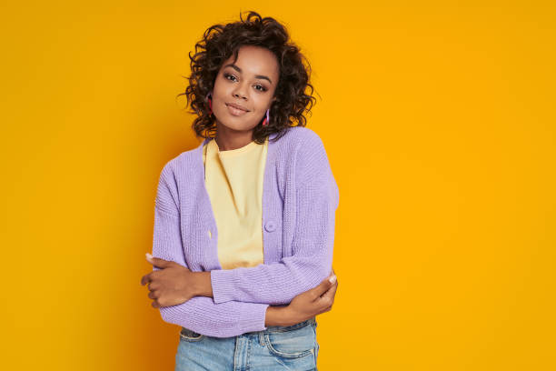 istock Beautiful African woman looking at camera while standing against yellow background 1422482035