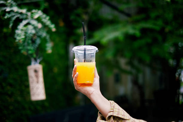 istock Woman hand holding out plastic cup with plant background. 1422486299