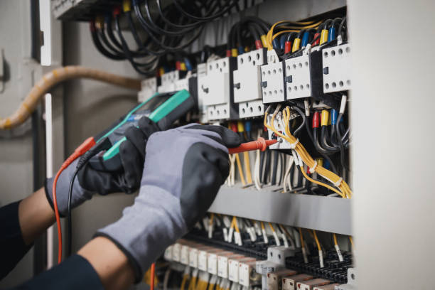 電気および電気メンテナンスサービス、回路ブレーカー端子とケーブル配線主配電盤で電流電圧をチェックするacマルチメータを保持するエンジニアの手。 - cable stitch ストックフォトと画像