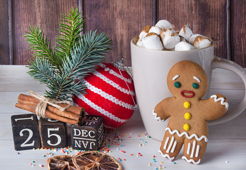 Christmas card made of gingerbread man, coffee, sweets and calendar on brown background. New Year and Christmas concept.