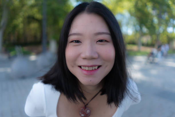 portrait de style de vie d’une jeune femme coréenne asiatique heureuse et belle souriant joyeusement à l’extérieur dans un parc de la ville - mid adult women human skin neat good condition photos et images de collection