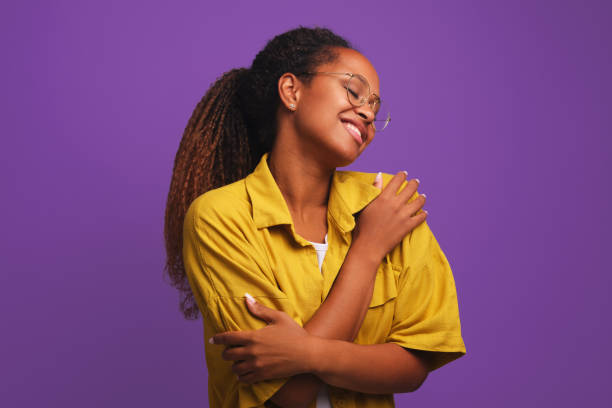 istock Young African American woman hugging herself closing eyes smiling in studio 1422493512