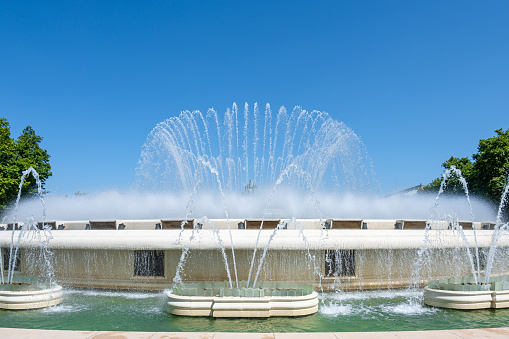 Fountain with angels statue in a sea garden park with grass and trees around it in Varna, Bulgaria.